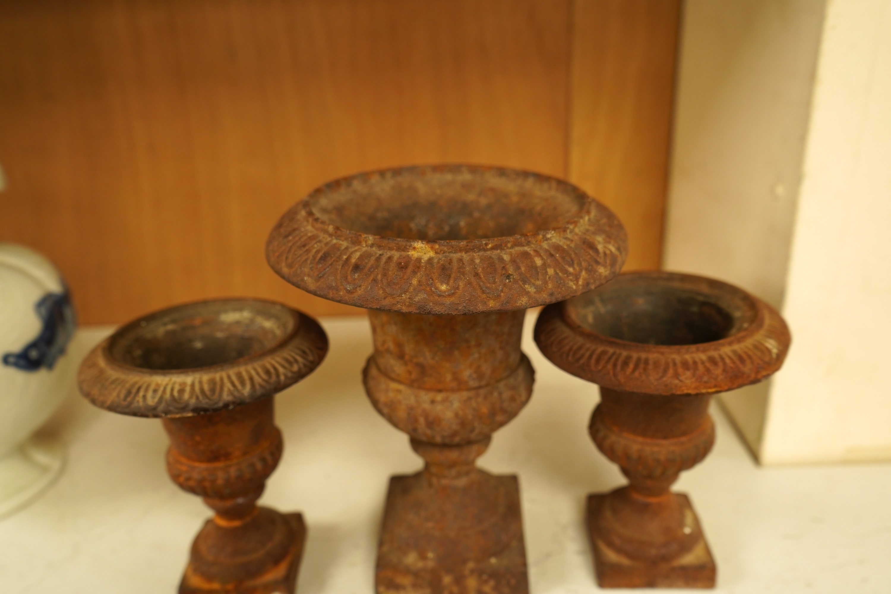 A garniture of three cast iron campana vases, largest 18cm high